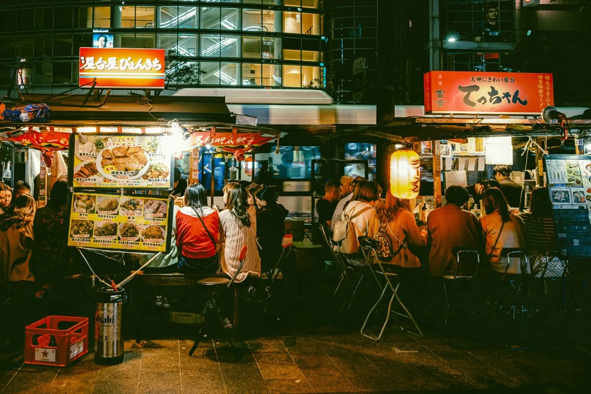 Yatai nocturnos iluminados junto al río en Nakasu, Fukuoka